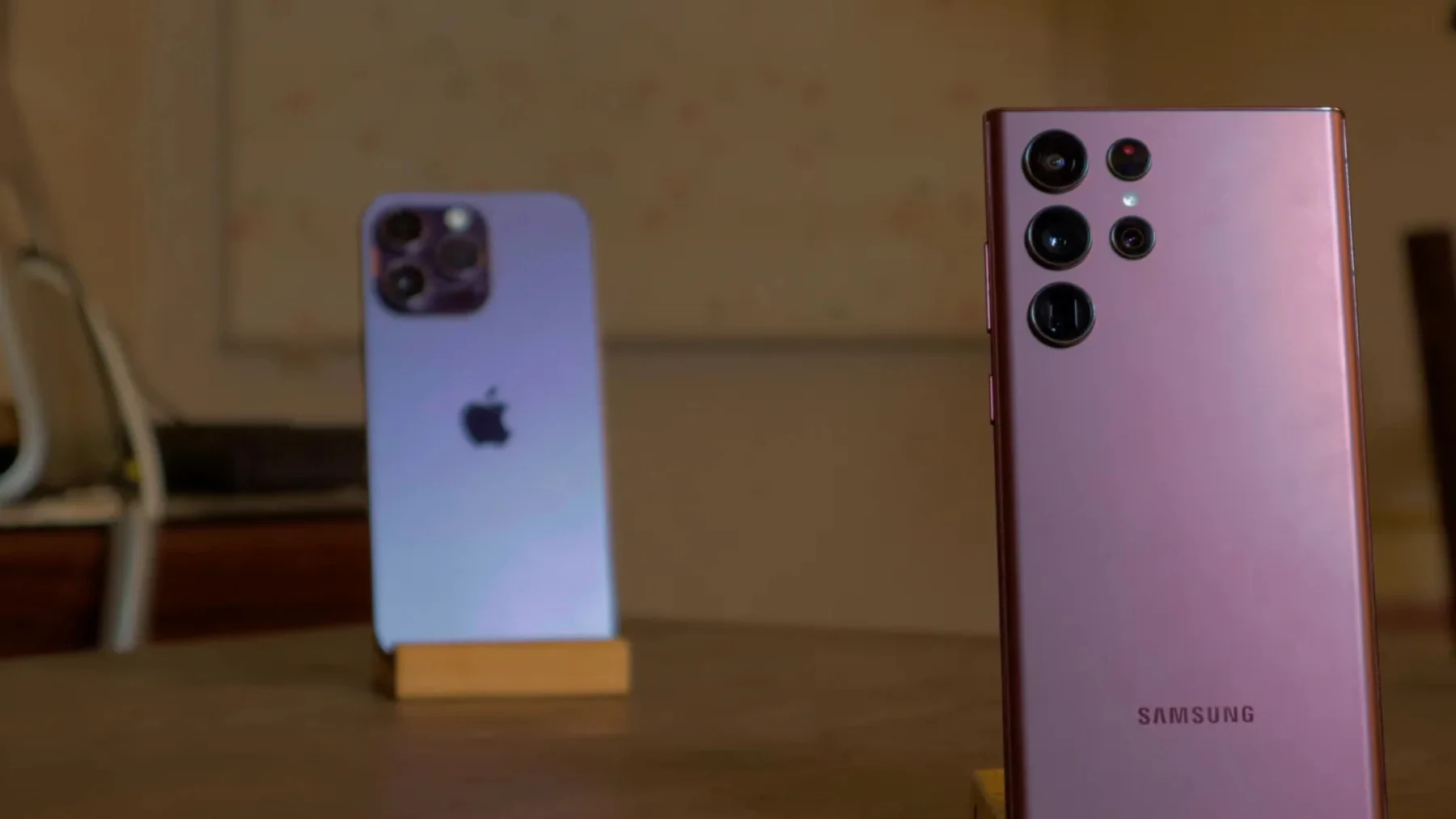 Blue iPhone and burgundy Samsung Galaxy S22 Ultra standing side by side